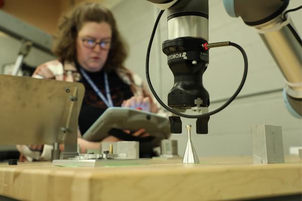 A female student cutting metal with machinery.